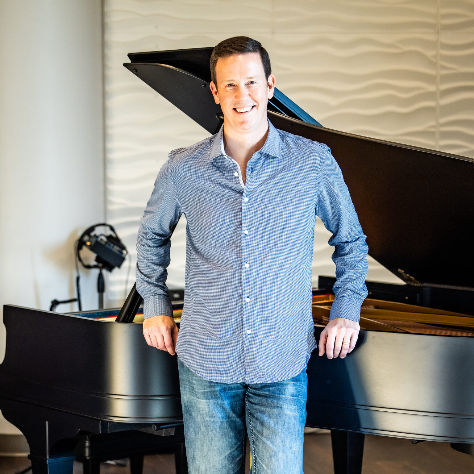 Pianist standing near the restored 1922 Baldwin Model C grand piano.