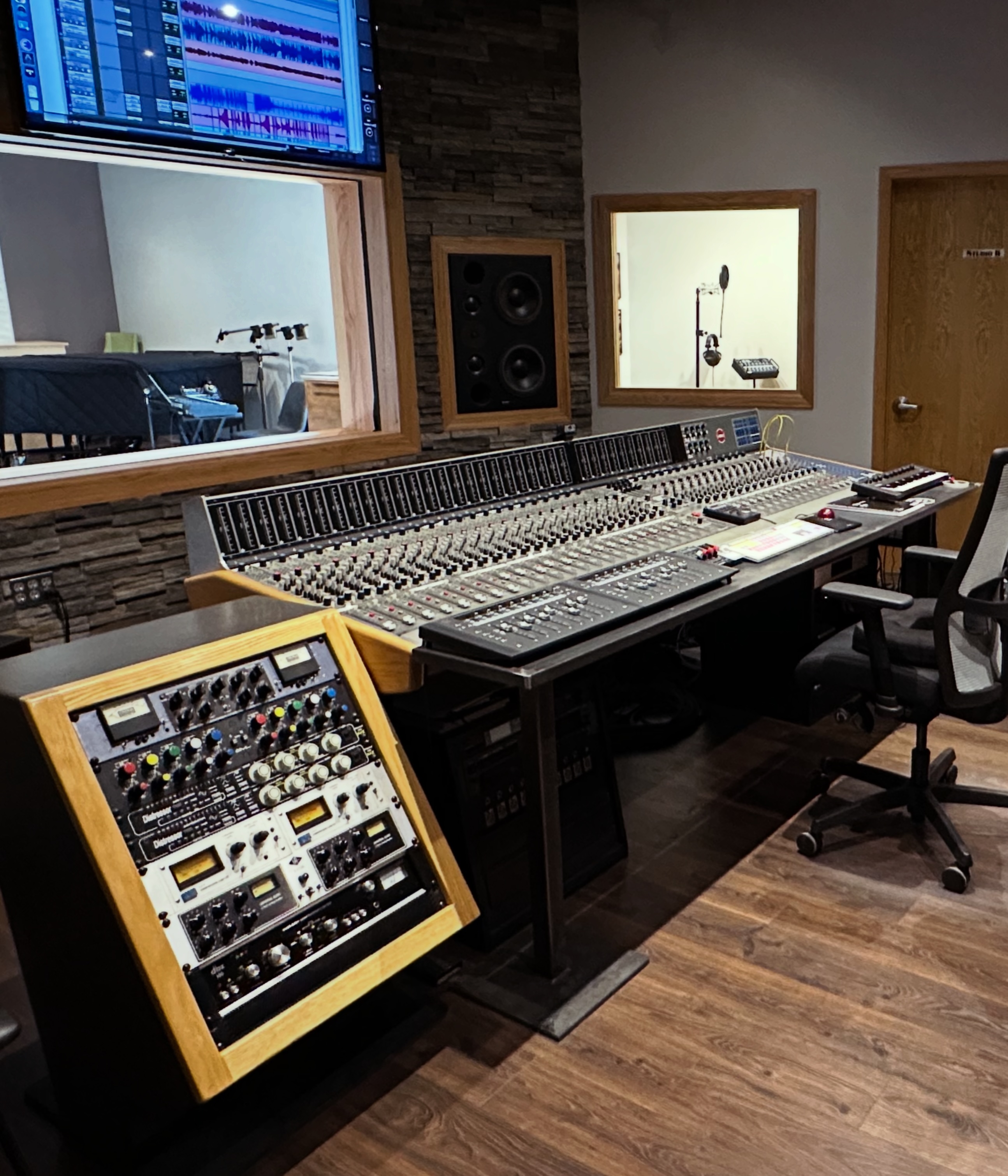 Perspective view of the control room, featuring the Sound Workshop Series 34 console, mastering rack of vintage stereo compressors, and insight into the live room and isolation booth.